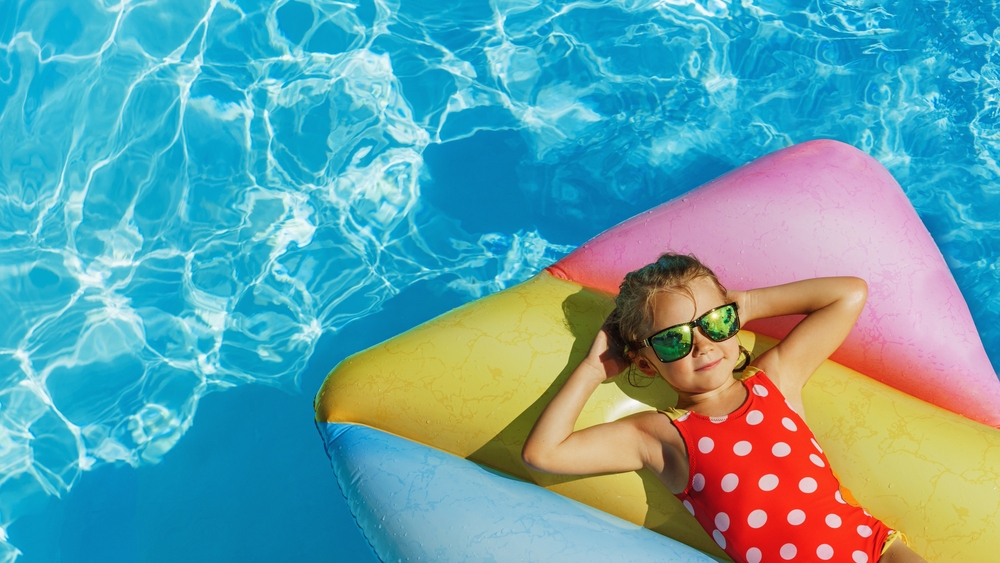 Child in swimming pool. Having fun on vacation at the hotel pool. Colorful vacation concept.